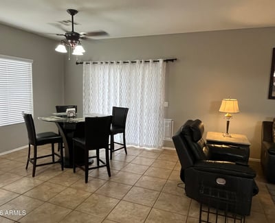 Dining area with large windows, tile flooring, ceiling fan, and convenient access to the covered patio creates a bright and comfortable setting for everyday dining.