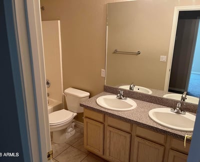 A dual-sink vanity, tile flooring, and a full tub and shower combination make this well-appointed bathroom ideal for everyday comfort and convenience.