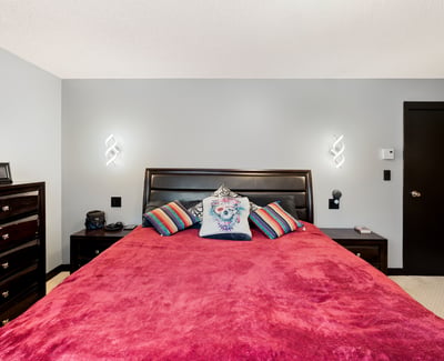 Spacious bedroom featuring a vibrant color palette, modern lighting, and ample storage for a cozy retreat.