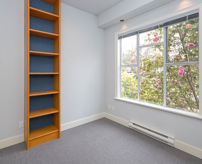Bright room featuring large windows, a built-in bookshelf, and views of vibrant landscaping. Perfect for a study or guest space.