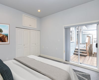 Bright bedroom features sliding doors leading to a private outdoor deck, perfect for relaxation and enjoyment.