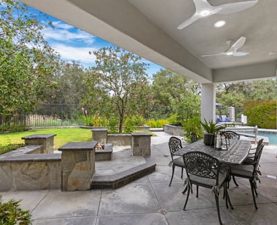 Spacious outdoor patio features a built-in firepit, ceiling fans and lighting perfect for gatherings and enjoying nature.