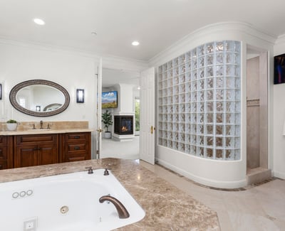 Primary Bathroom-Luxurious bathroom featuring a jetted tub, modern glass block shower, and ample natural light.
