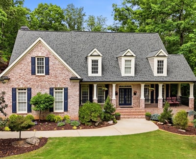 Beautiful brick home nestled in nature, featuring a spacious porch and well-maintained landscaping in a peaceful setting.