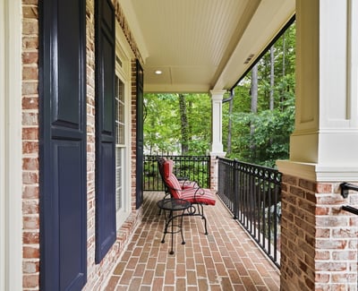Inviting porch space with brick flooring and views of lush greenery, perfect for outdoor relaxation.