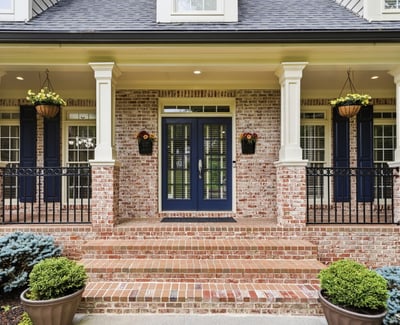 Welcoming entrance features a brick facade, dual blue doors, and attractive landscaping for a polished look.