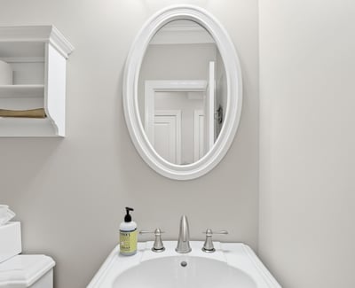 Bright, well-maintained bathroom featuring modern fixtures and a circular mirror, perfect for everyday use.