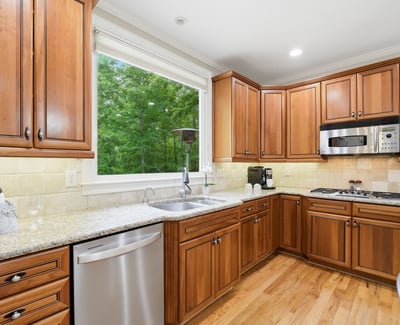 Bright kitchen featuring custom wood cabinetry, modern appliances, and ample counter space overlooking a lush outdoor view.