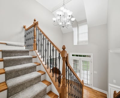Bright and inviting entryway features a spacious staircase with elegant railings and abundant natural light.