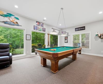Spacious game room featuring a billiards table and large windows that invite natural light.