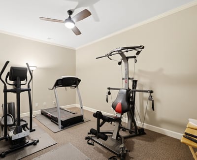 Spacious workout room featuring modern fitness equipment and ample natural light, perfect for home exercise routines.