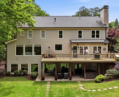 Spacious home with expansive outdoor deck, large windows, and a beautifully landscaped backyard ideal for gatherings.