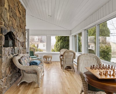 Bright, sunlit sunroom featuring expansive windows, natural stone accents, and inviting seating for relaxation or play.