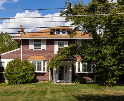 Spacious home featuring a well-maintained lawn, mature trees, and a welcoming entrance, perfect for family living.