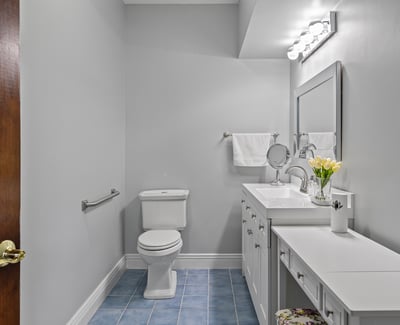 Bright and functional bathroom featuring modern fixtures, ample storage, and sleek blue tile flooring.