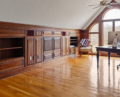 Bright, spacious office featuring wooden paneling, ample storage, and large windows for natural light.