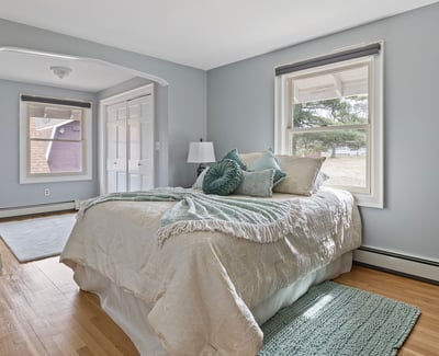 Bright bedroom featuring large windows, natural light, and ample closet space, perfect for relaxation and comfort.