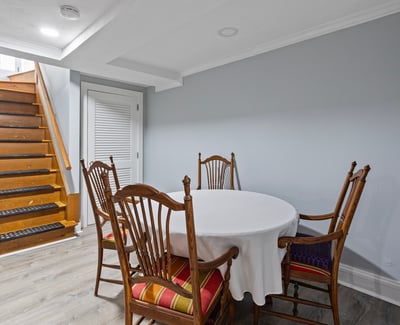 Spacious dining area features a round table and wooden staircase leading to additional living spaces.
