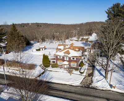 Spacious home nestled in a snowy landscape, featuring ample outdoor space and convenient access to the road.
