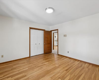 Light-filled room with hardwood floors, featuring ample closet space and simple, versatile decor options.