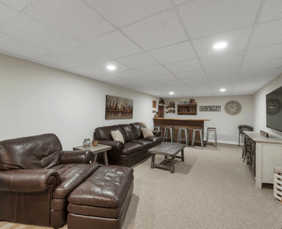 Spacious finished basement features cozy seating, a bar area, and modern lighting, perfect for entertaining.