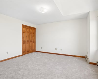 Spacious room filled with natural light, featuring neutral tones and ample storage options for versatile use.