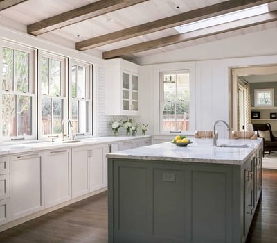 Bright and airy kitchen featuring sleek cabinetry, a large island, and natural light from skylights.