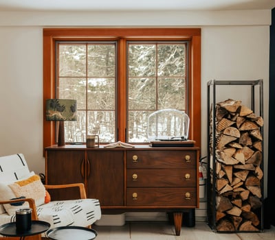 Bright and inviting space with natural light, featuring a cozy reading nook and rustic wood storage.