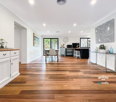 Spacious open-concept living area with warm wooden floors and abundant natural light, ideal for entertaining.