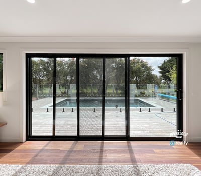 Bright and inviting living space with expansive glass doors opening to a private pool and outdoor deck.