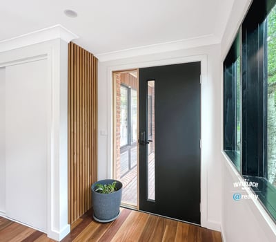 Contemporary entryway featuring a sleek front door and natural light enhancing the warm wooden floors.