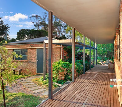 Spacious covered porch leads to a well-maintained garden, offering a welcoming entry to this unique property.