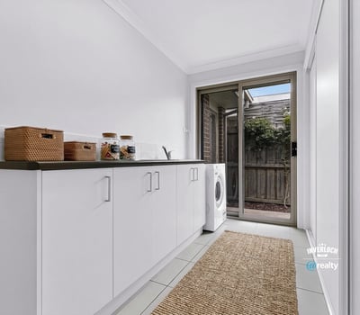 Light-filled laundry room featuring ample storage, modern appliances, and direct access to an outdoor area.