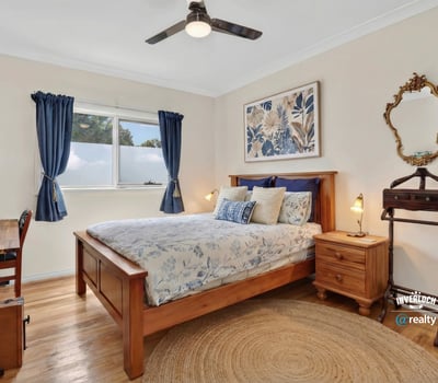 Cozy bedroom featuring a wooden bed, natural light, and a functional workspace for relaxation or productivity.