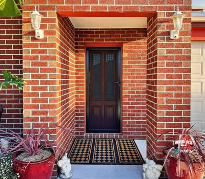 Discover a welcoming entryway framed by vibrant greenery and warm brick accents, perfect for inviting guests.