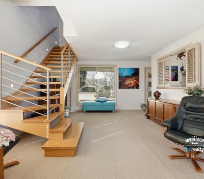 Spacious living area with inviting staircase and large windows offering ample natural light.