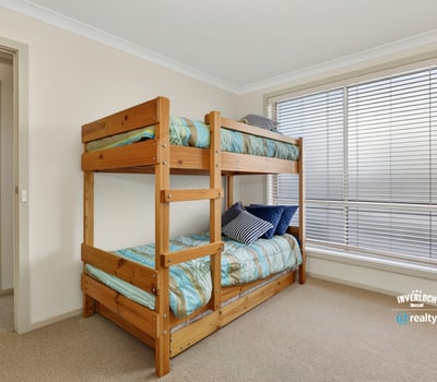 Cozy bedroom featuring a sturdy bunk bed and ample natural light from large windows.