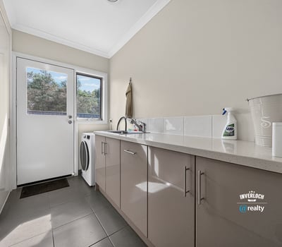 Bright laundry area featuring modern cabinets, ample counter space, and convenient outdoor access.