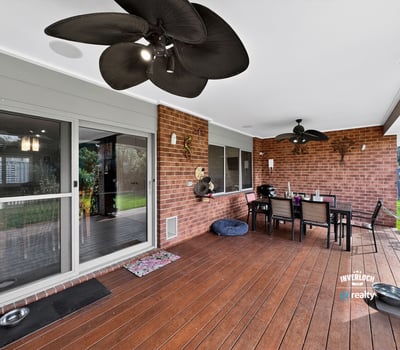 Spacious covered patio perfect for outdoor dining, featuring ceiling fans and a view of the lawn.