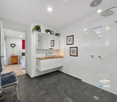 Modern bathroom featuring spacious walk-in shower, dual rainfall showerheads, and sleek cabinetry for organized storage.