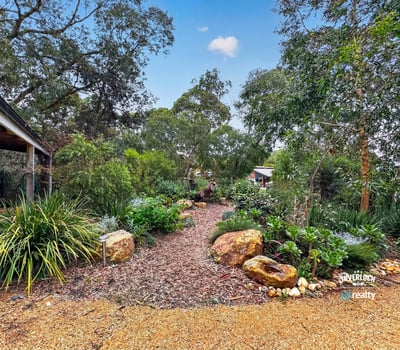 This landscaped garden features diverse plantings and unique stone accents, creating a vibrant outdoor oasis.