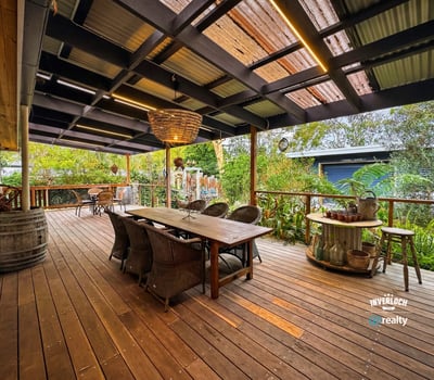 Spacious outdoor entertaining area featuring a large dining table, surrounded by lush greenery and a cozy atmosphere.