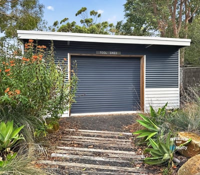 This functional tool shed offers practical storage solutions, surrounded by lush landscaping and natural beauty.