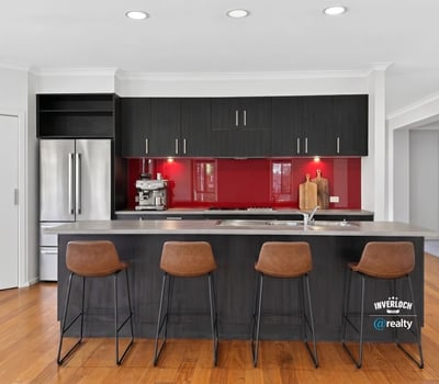 Modern kitchen featuring sleek cabinetry, a striking red backsplash, and spacious island with bar seating.