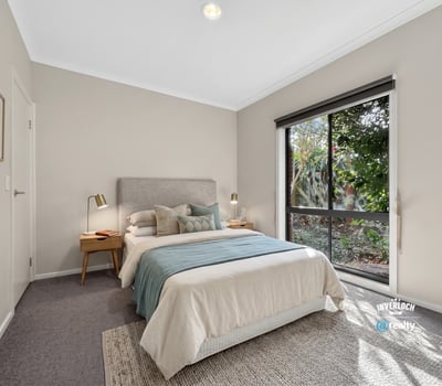 Bright bedroom featuring large windows, cozy furnishings, and a peaceful view of the outdoor greenery.