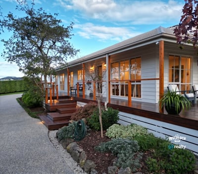This inviting home features a spacious porch, landscaped gardens, and ample natural light throughout.
