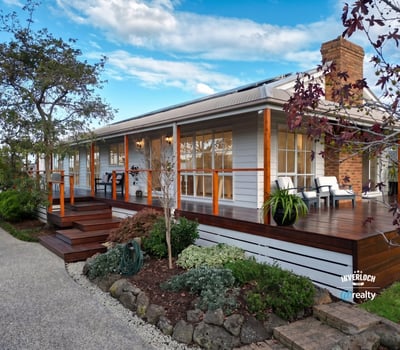 Inviting home features a spacious deck, landscaped garden, and picturesque setting, perfect for outdoor living.