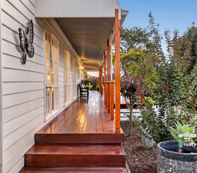 Experience the inviting atmosphere of this well-appointed home with a spacious front porch and lush surroundings.