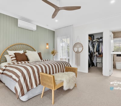 Spacious bedroom featuring unique decor, natural light, and convenient access to an organized closet and bathroom.