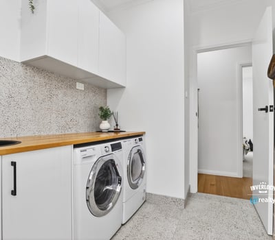 Bright laundry area featuring modern appliances, streamlined cabinetry, and a clean, functional design.